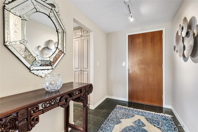 foyer entrance with dark tile patterned flooring and track lighting