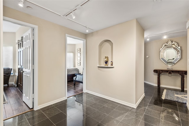 corridor featuring dark hardwood / wood-style flooring and rail lighting