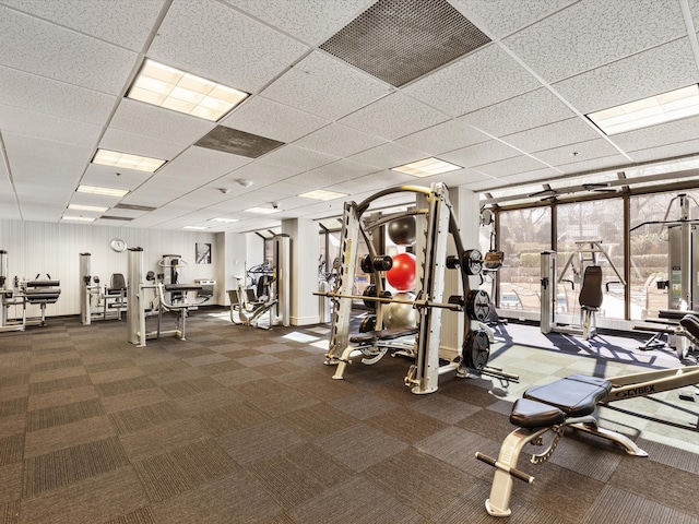 exercise room featuring dark carpet and a drop ceiling