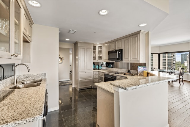 kitchen featuring sink, kitchen peninsula, black appliances, light stone countertops, and cream cabinets