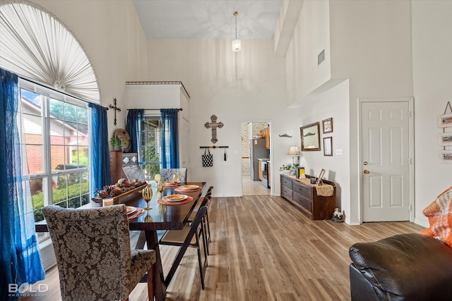 dining area featuring a towering ceiling and hardwood / wood-style floors