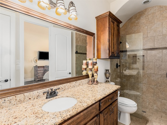 bathroom featuring vanity, tiled shower, and toilet