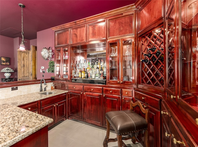 bar with sink, light tile patterned flooring, light stone counters, and decorative light fixtures