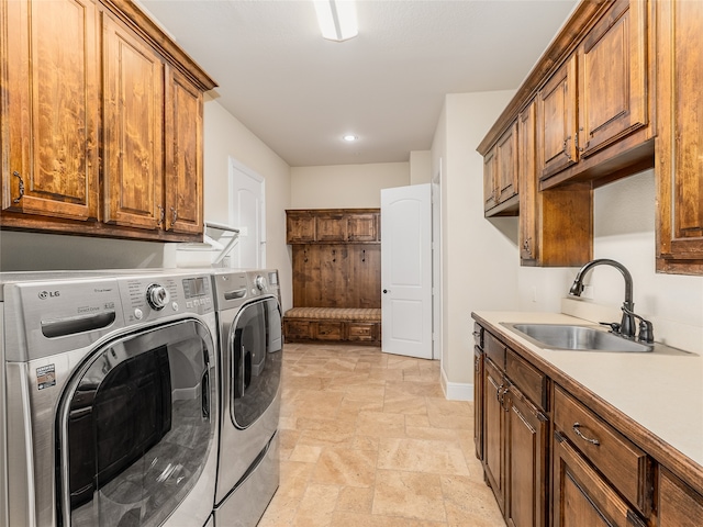 clothes washing area with cabinets, sink, and washing machine and dryer