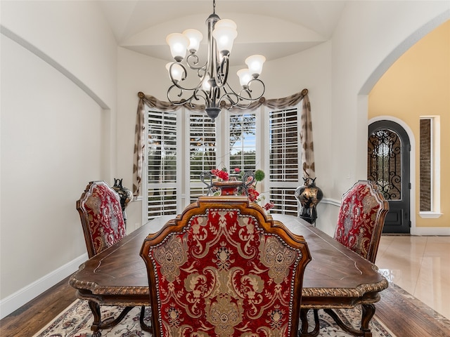 dining area with hardwood / wood-style flooring, lofted ceiling, and a chandelier