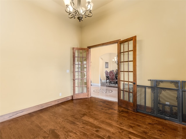 unfurnished room featuring french doors, hardwood / wood-style floors, and a chandelier