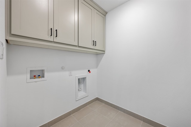 clothes washing area featuring light tile patterned floors, hookup for an electric dryer, washer hookup, baseboards, and cabinet space