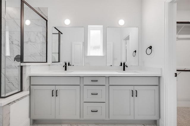 full bathroom featuring a sink, a marble finish shower, and double vanity