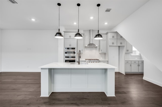 kitchen with pendant lighting, light countertops, visible vents, a sink, and wall chimney exhaust hood