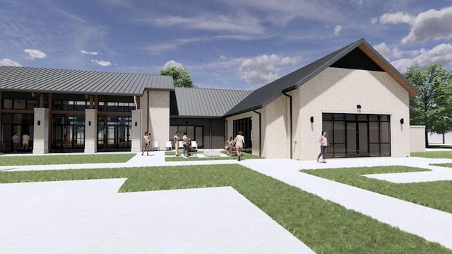 rear view of property featuring a standing seam roof, metal roof, a lawn, and stucco siding