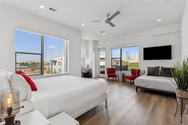 bedroom featuring ceiling fan, hardwood / wood-style floors, and multiple windows