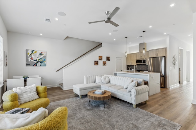 living room featuring sink, hardwood / wood-style floors, and ceiling fan