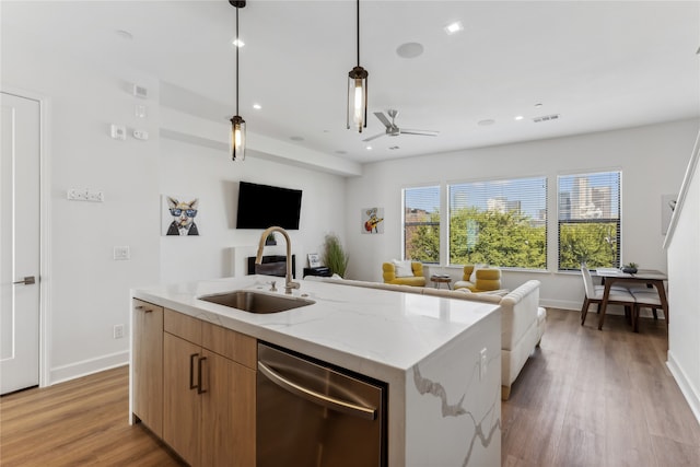 kitchen with sink, decorative light fixtures, a center island with sink, stainless steel dishwasher, and light stone countertops