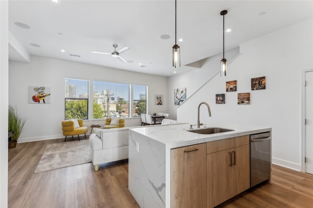 kitchen featuring sink, light stone countertops, an island with sink, dark hardwood / wood-style flooring, and stainless steel dishwasher