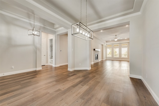 unfurnished dining area featuring ceiling fan, hardwood / wood-style flooring, a tray ceiling, and ornamental molding