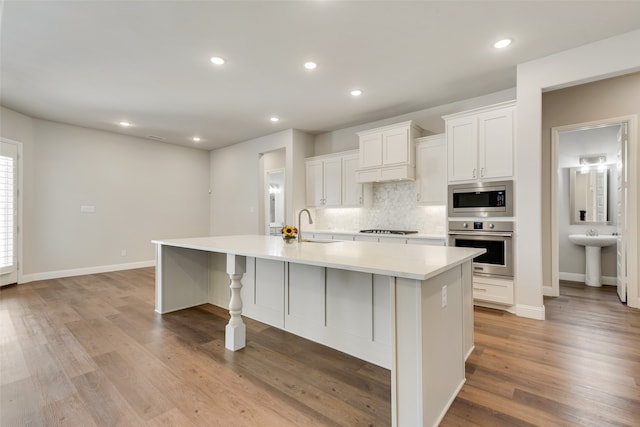 kitchen featuring a large island, stainless steel appliances, white cabinets, and light hardwood / wood-style flooring