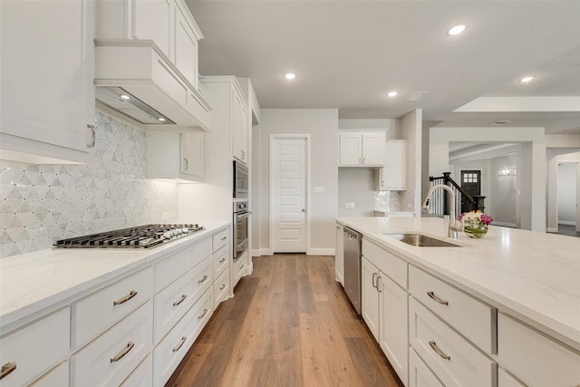 kitchen featuring white cabinets, light hardwood / wood-style flooring, stainless steel appliances, and light stone counters