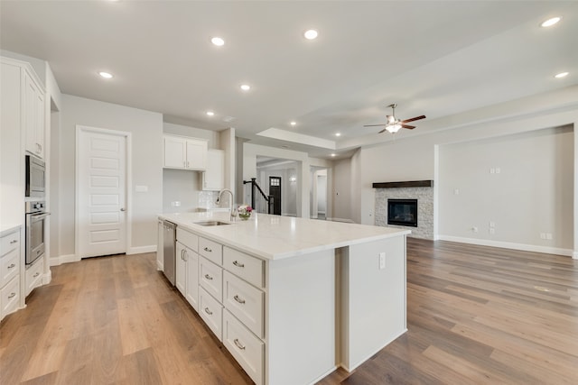 kitchen with ceiling fan, white cabinets, an island with sink, sink, and stainless steel appliances