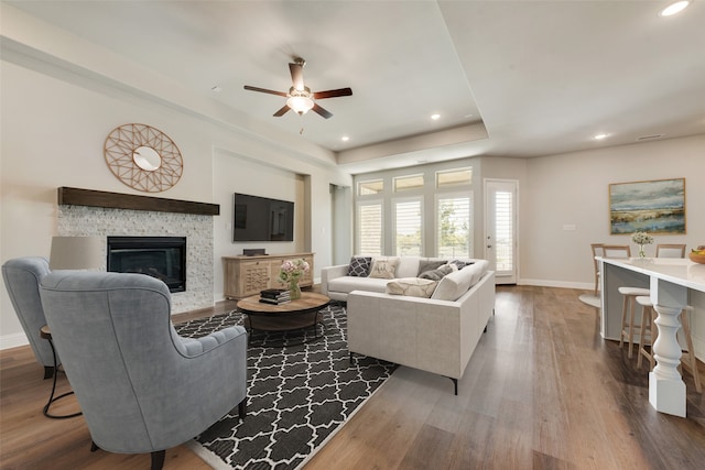 living room with wood-type flooring, ceiling fan, and a fireplace