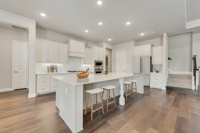 kitchen featuring appliances with stainless steel finishes, a center island with sink, and white cabinetry