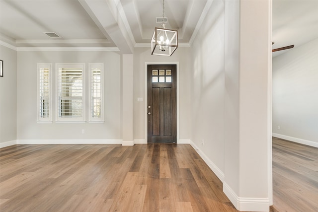 entrance foyer featuring an inviting chandelier, ornamental molding, and hardwood / wood-style floors