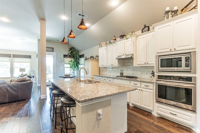 kitchen with stainless steel appliances, an island with sink, sink, and white cabinets