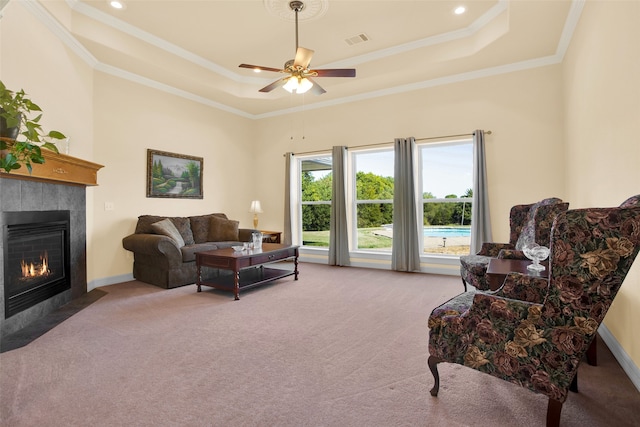 carpeted living room featuring ceiling fan, a fireplace, a raised ceiling, and ornamental molding