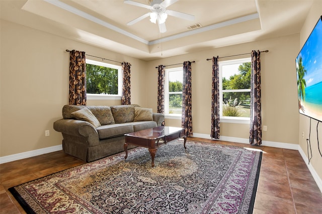 tiled living room with crown molding, a tray ceiling, and ceiling fan