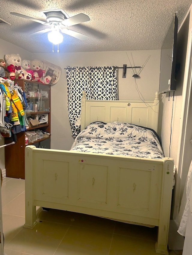 tiled bedroom with ceiling fan and a textured ceiling