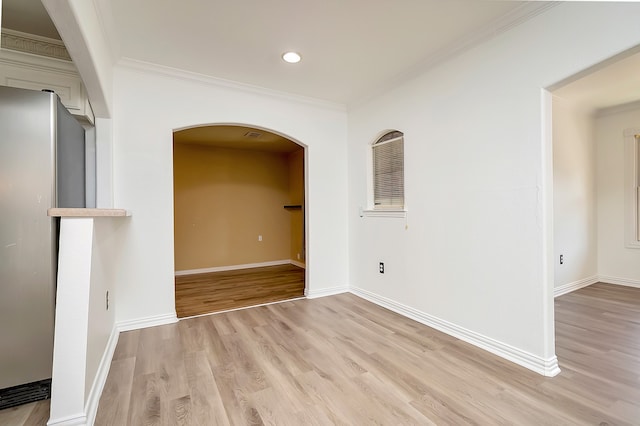 empty room with light wood-type flooring and crown molding