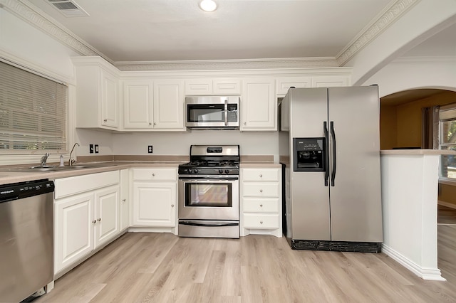 kitchen with appliances with stainless steel finishes, light hardwood / wood-style floors, white cabinets, crown molding, and sink