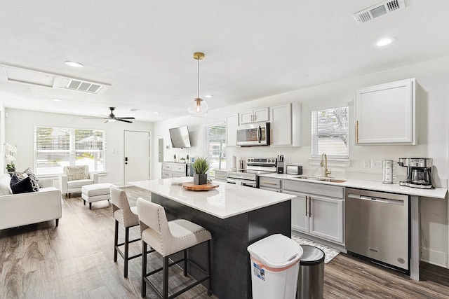 kitchen with a kitchen bar, stainless steel appliances, sink, decorative light fixtures, and a center island