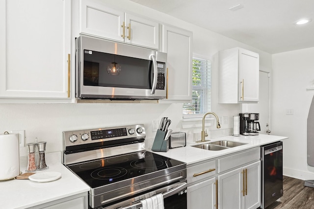 kitchen with sink, dark hardwood / wood-style flooring, pendant lighting, white cabinets, and appliances with stainless steel finishes