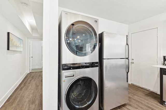 washroom with stacked washer / dryer and light hardwood / wood-style flooring