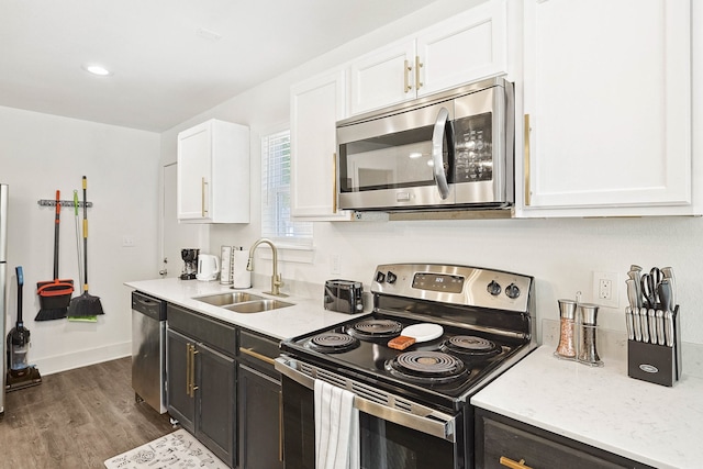 kitchen with light stone countertops, sink, dark wood-type flooring, white cabinets, and appliances with stainless steel finishes