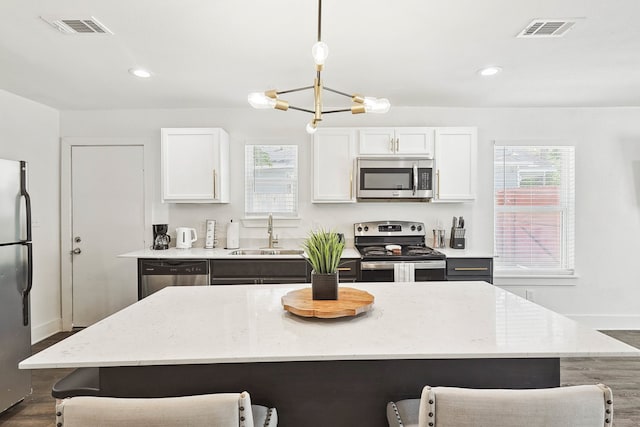 kitchen with decorative light fixtures, sink, white cabinetry, and stainless steel appliances