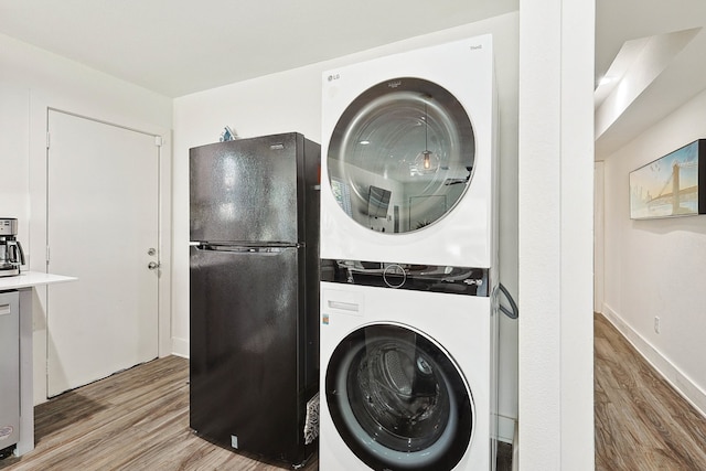 laundry room with light wood-type flooring and stacked washer / dryer