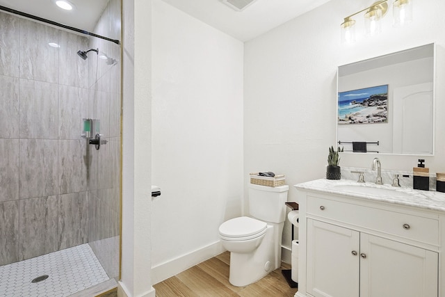 bathroom featuring tiled shower, toilet, vanity, and hardwood / wood-style flooring