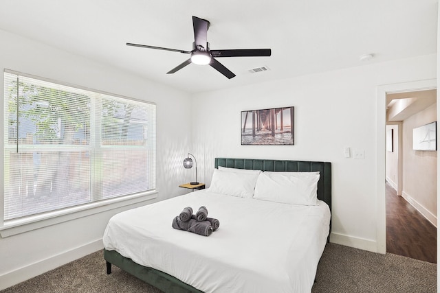 bedroom with multiple windows, ceiling fan, and dark colored carpet