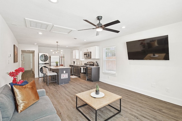 living room featuring ceiling fan, sink, light hardwood / wood-style flooring, and stacked washer and clothes dryer