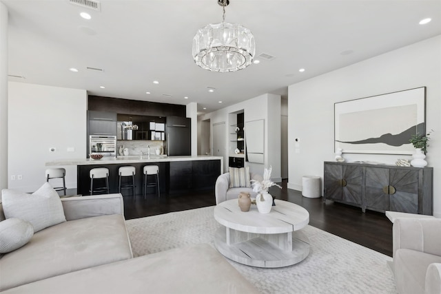 living room featuring sink, dark hardwood / wood-style flooring, and a notable chandelier