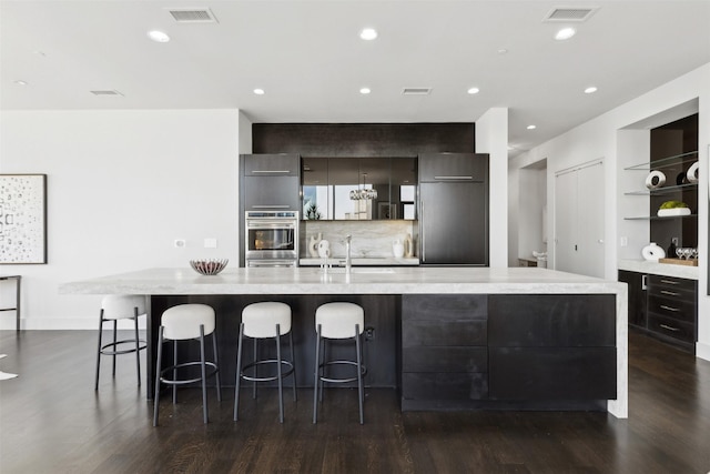 kitchen with a breakfast bar, built in fridge, a spacious island, and built in shelves