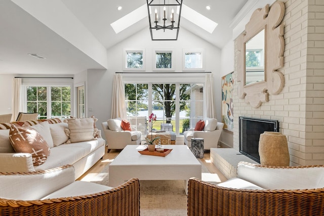 living room with a brick fireplace, a wealth of natural light, light hardwood / wood-style flooring, and high vaulted ceiling