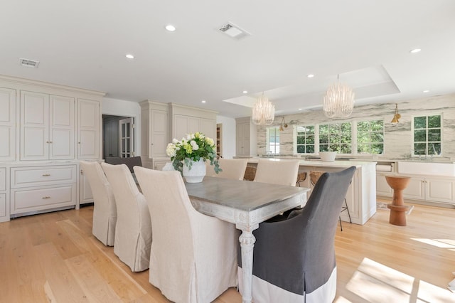 dining space featuring light wood-type flooring and an inviting chandelier