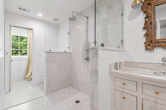 bathroom with tiled shower and vanity