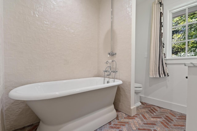 bathroom featuring tile walls, toilet, and a washtub