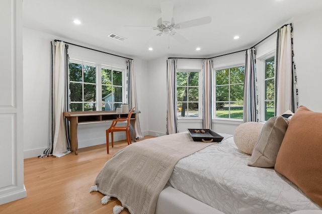 bedroom featuring light hardwood / wood-style flooring, ceiling fan, and multiple windows