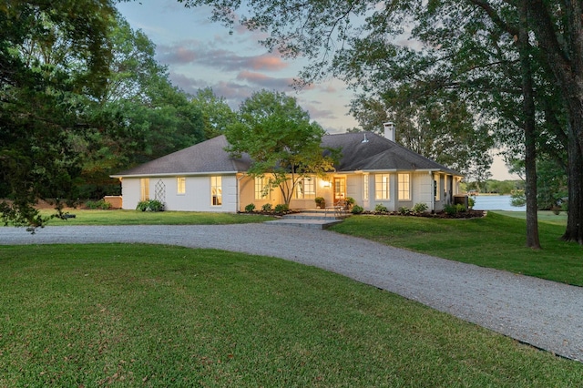 single story home featuring a lawn and a water view