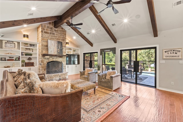 living room featuring ceiling fan, beam ceiling, wood-type flooring, a stone fireplace, and french doors