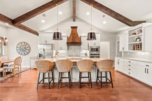 kitchen with pendant lighting, hardwood / wood-style flooring, tasteful backsplash, beam ceiling, and appliances with stainless steel finishes